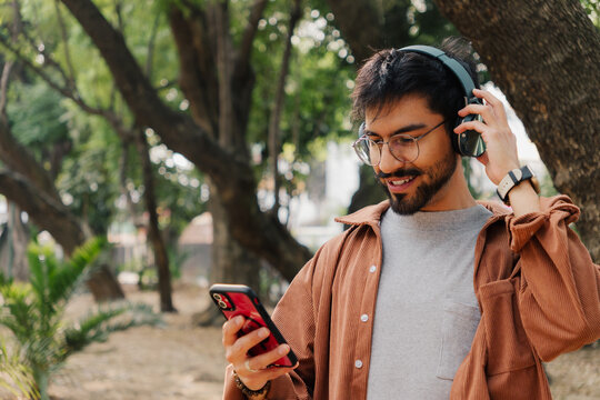 Young man listening to music with headphones in the park.