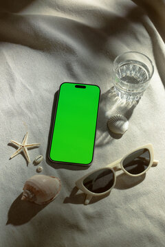 Smartphone with green screen on a textured surface with beach