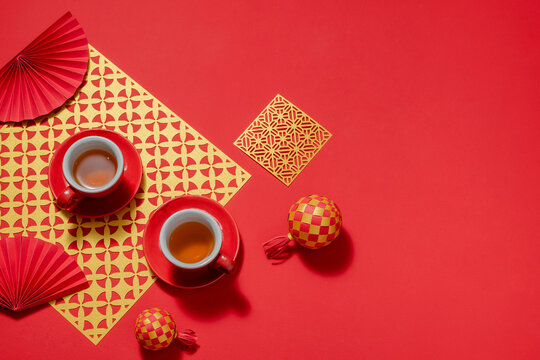 Chinese New Year tea setting with red cups, fans, and decorations