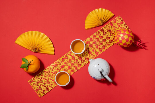 Chinese New Year still life with tea set, fans, and orange on red