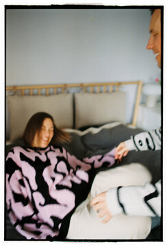 Woman laughing playfully on bed during couple time