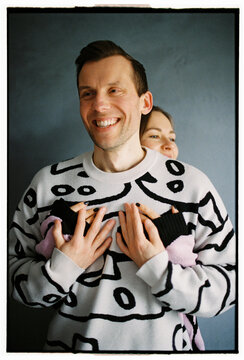 Smiling couple in cozy hug in front of blue wall