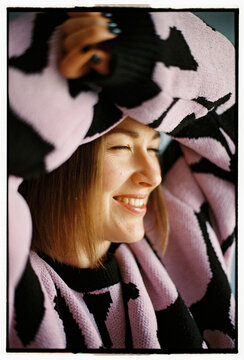 Close-up of smiling woman with arms above head in cozy sweater