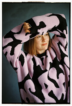 Woman looks away with arms above head in cozy sweater