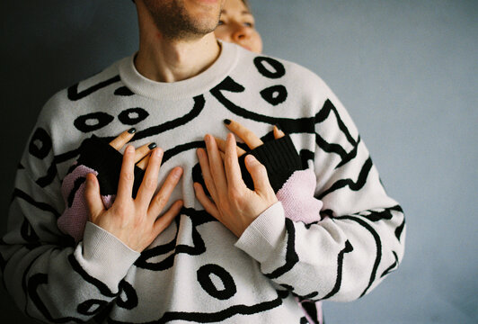 Anonymous woman hugs man from behind with hands on his chest