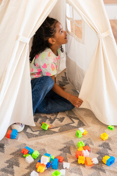 Child playing in tent with colorful building blocks