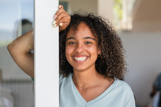 Smiling woman leaning against a doorframe indoors