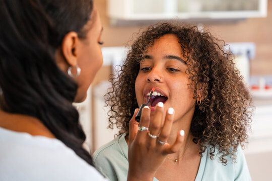 Applying lipstick in a cozy home environment