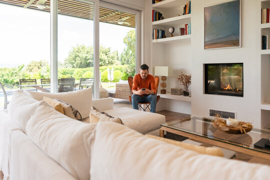 Modern living room with man seated by large windows