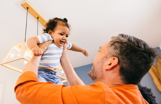 Father lifting joyful baby in bright modern home