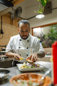 Professional chef plating restaurant dish in kitchen