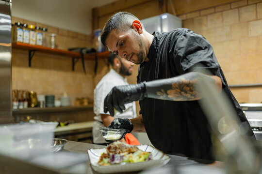 Chef plating gourmet dish in a professional restaurant kitchen