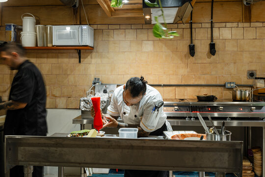 Chef garnishing dish in professional restaurant kitchen