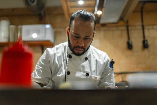 Male cook concentrating on preparing customer order