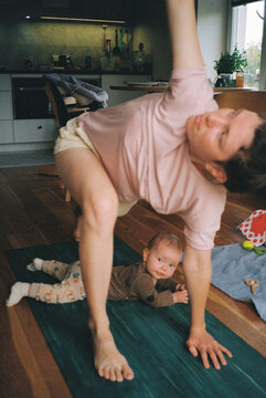 Young woman doing yoga and baby lying on the mat