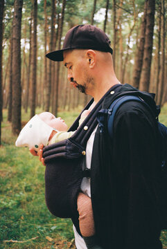 Father holding baby in a carrier in the forest