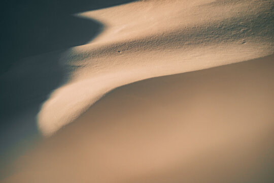 Snow dune patterns create shapes in sunlight at a desert location
