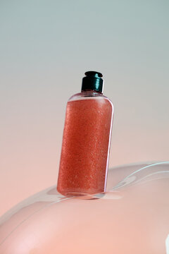 Clear bottle with pink shimmering liquid and dark green cap