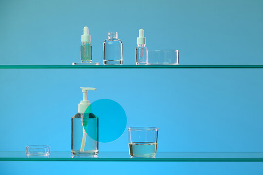 Clear glass bottles and containers arranged on shelves against a blue