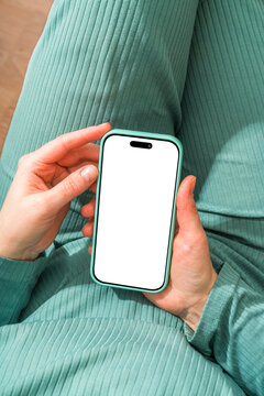 Person Holding Smartphone with Blank Screen in Green Outfit
