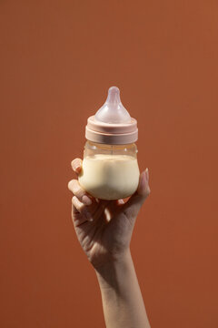 A person's hand gently cradles baby milk bottle 