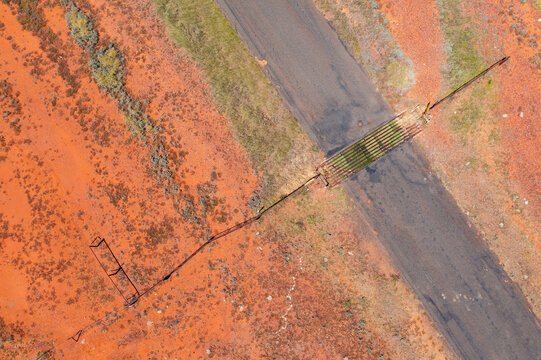 Cattle grid and fenceline crossing a narrow road in the outback 