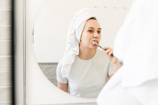 Woman Brushing Teeth with Towel on Head After Shower