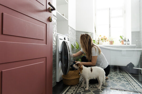 Woman Doing Laundry with Dog in Modern Bathroom