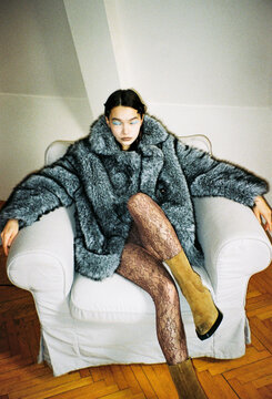 Woman Sitting on a Chair Wearing a Fur Coat With Patterned Tights