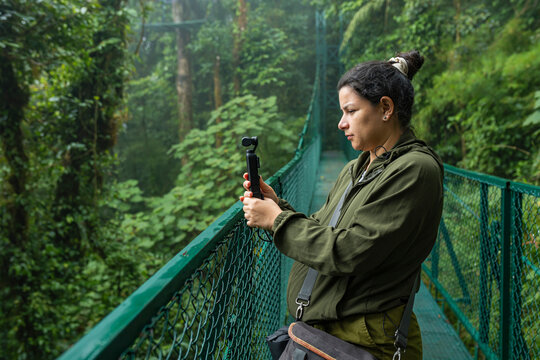 Content creator using an action camera on a tropical hanging bridge
