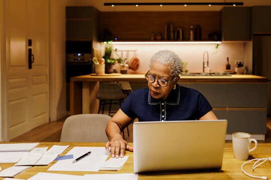 Senior woman managing finances while using laptop at home
