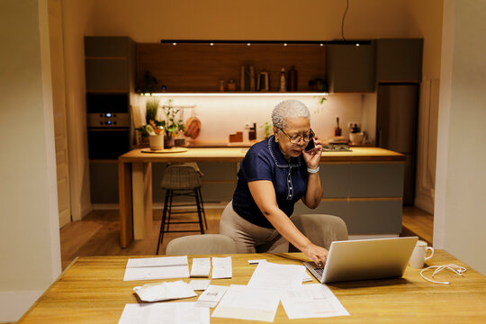 Senior woman multitasking financial paperwork and phone call