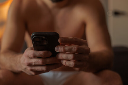 Man Checks Phone While Sitting Indoors In Morning