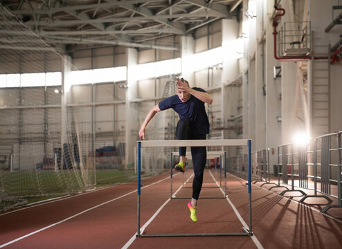 Male athlete jumping over barrier