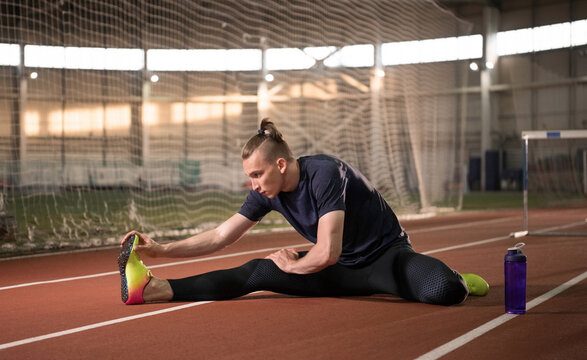 Male athlete stretching on track