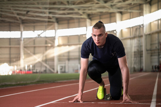 Determined male runner in crouch start position on track