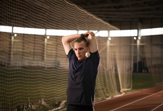 Sportsman stretching arms during training