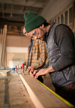Male carpenters measuring wooden board