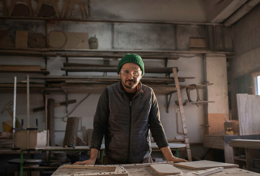 Male carpenter leaning on workbench