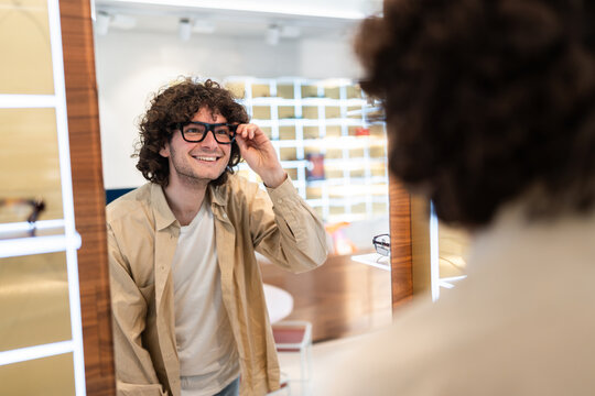Young man trying on eyeglasses in optical shop