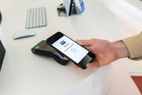 Customer making contactless payment using smartphone in optical shop