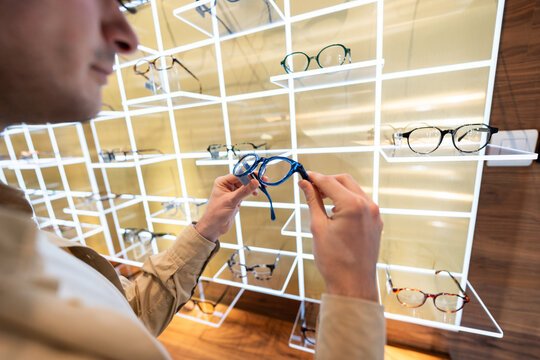 Man selecting new eyeglasses in optical shop