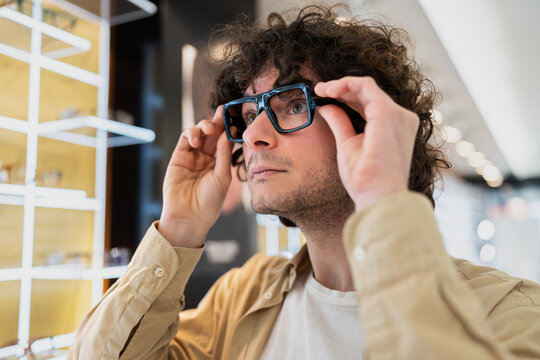 Young man trying on new eyewear in optical shop