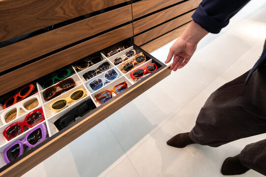 Hand opening wooden drawer with many colorful sunglasses