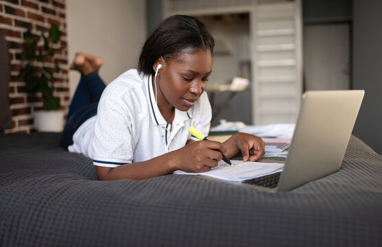 Black student making notes during online lesson