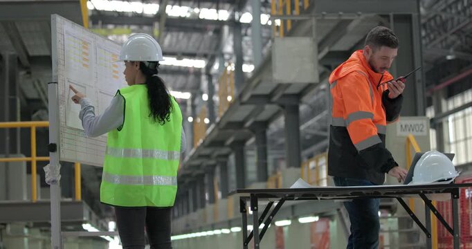 Rail engineers engaged in a planning and review session, focusing on a board displaying schedules, maintenance plans, and performance data of the rail systems. Ensuring efficient rail operations.
