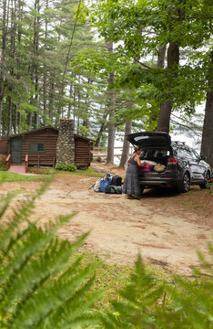 Woman vacation packing car at log cabin