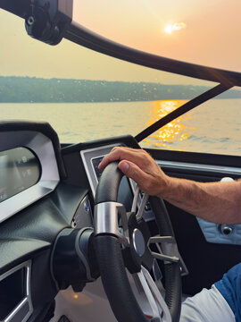 Hand on boat steering wheel at lake 