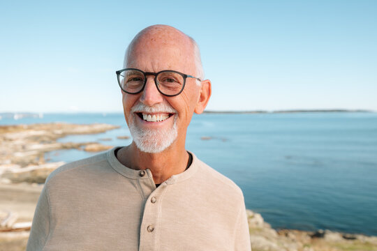 Candid portrait of a smiling elderly man by the sea, relaxed