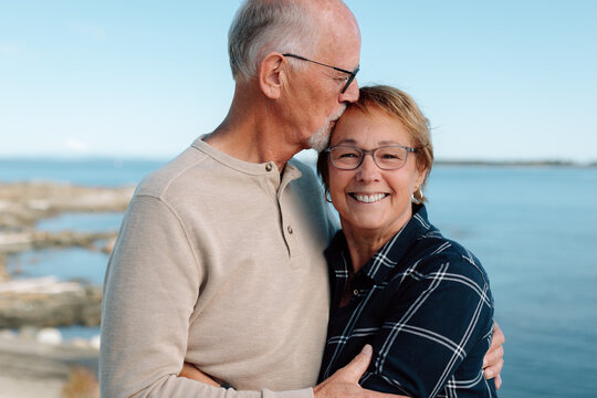 Candid couple by the sea sharing a kiss and warm embrace